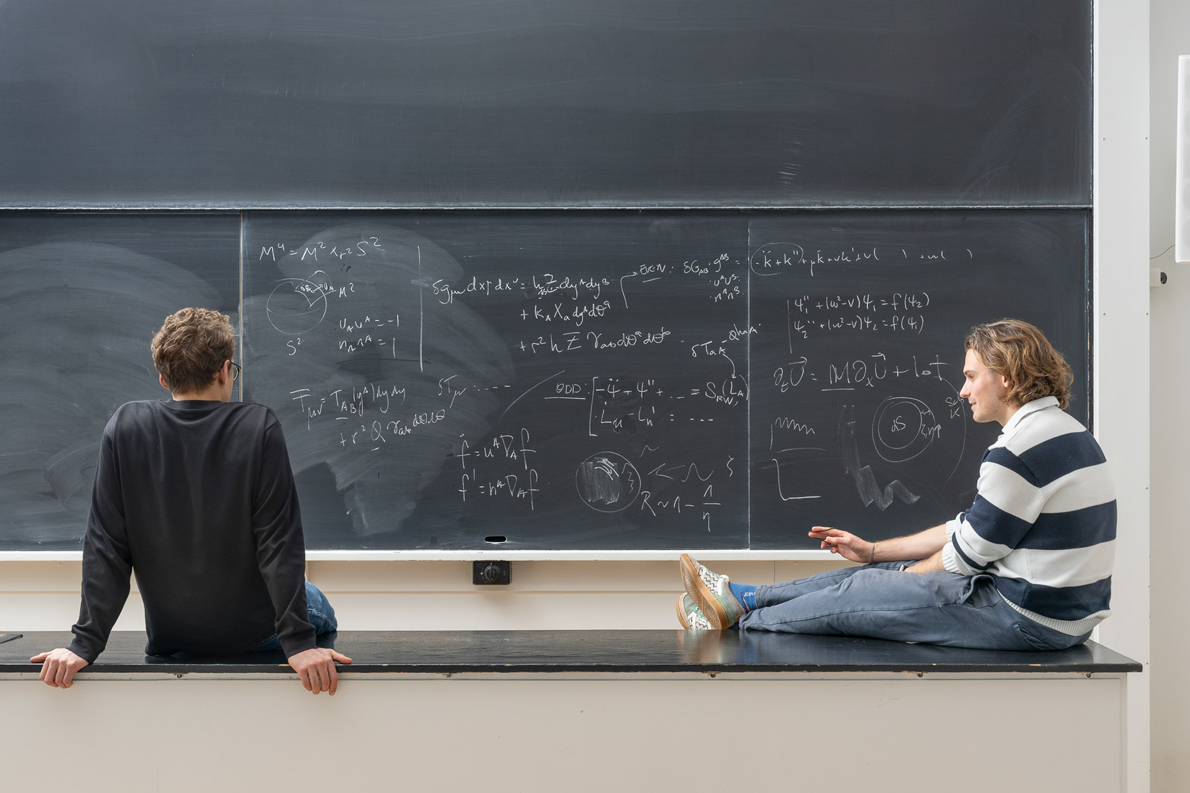 two physicsist stare at a blackboard